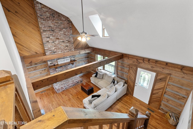 living room with hardwood / wood-style floors, ceiling fan, lofted ceiling, and wood walls