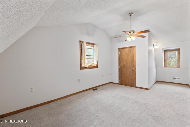 bonus room featuring light carpet, lofted ceiling, ceiling fan, and a healthy amount of sunlight