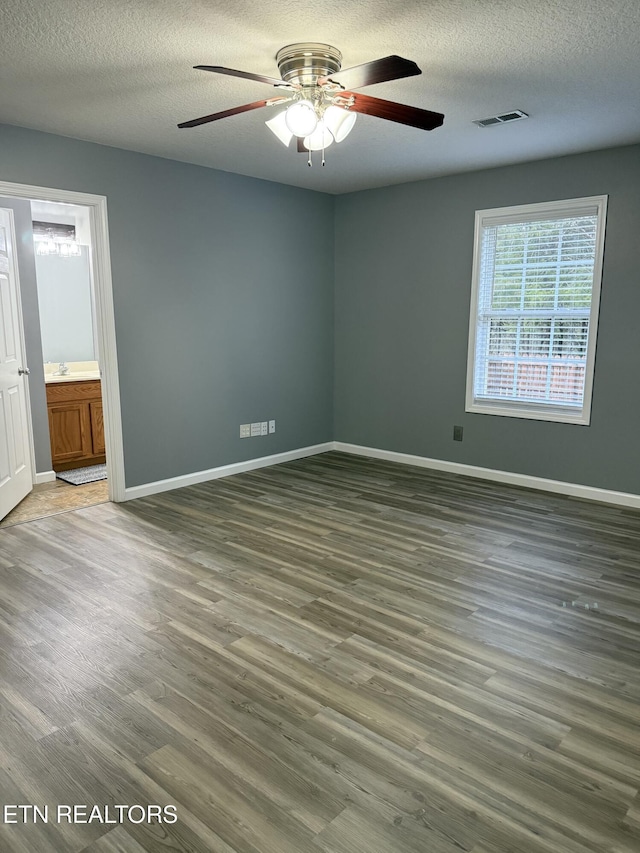 spare room featuring ceiling fan, dark hardwood / wood-style flooring, and a textured ceiling