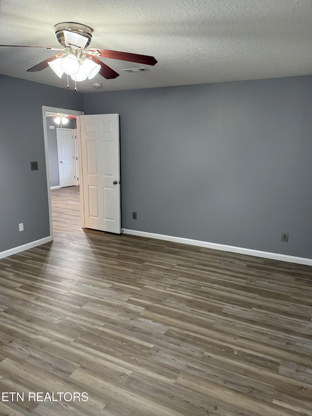 spare room with a textured ceiling, ceiling fan, and dark wood-type flooring