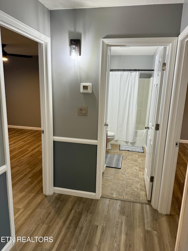 bathroom featuring hardwood / wood-style flooring, toilet, and shower / bath combo with shower curtain