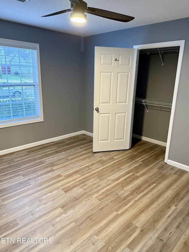 unfurnished bedroom with ceiling fan, light hardwood / wood-style floors, and a closet