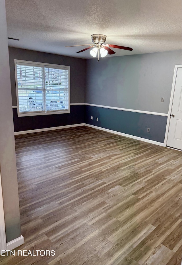 spare room featuring ceiling fan, wood-type flooring, and a textured ceiling