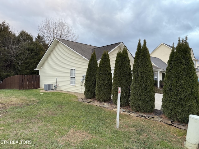 view of side of property featuring central air condition unit and a yard