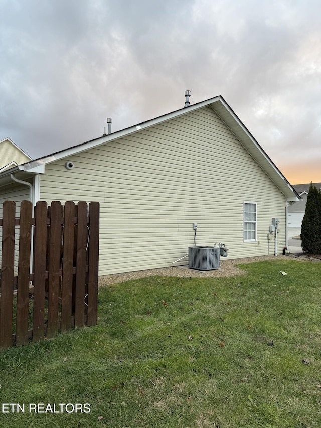 view of property exterior with central AC unit and a lawn