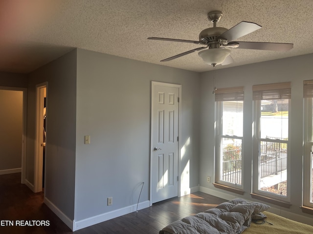 interior space with a textured ceiling, ceiling fan, and dark wood-type flooring