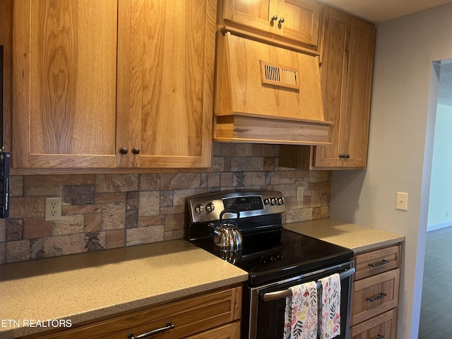 kitchen with stainless steel electric stove, decorative backsplash, and custom exhaust hood