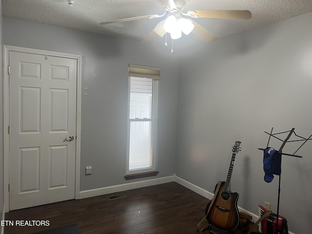 spare room featuring ceiling fan, a textured ceiling, and dark wood-type flooring