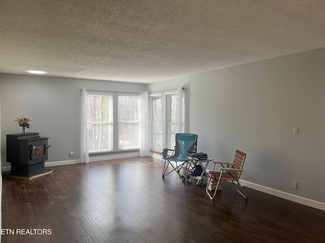 unfurnished room with dark hardwood / wood-style flooring, a textured ceiling, and a wood stove