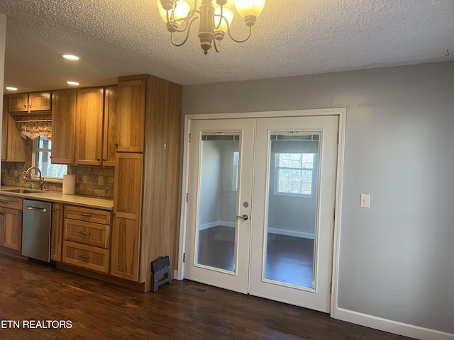 kitchen featuring sink, tasteful backsplash, stainless steel dishwasher, a notable chandelier, and a textured ceiling