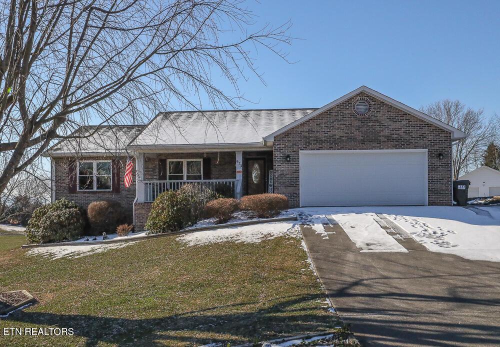 ranch-style home featuring a porch, a front yard, and a garage