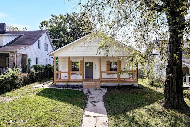 bungalow featuring covered porch and a front yard