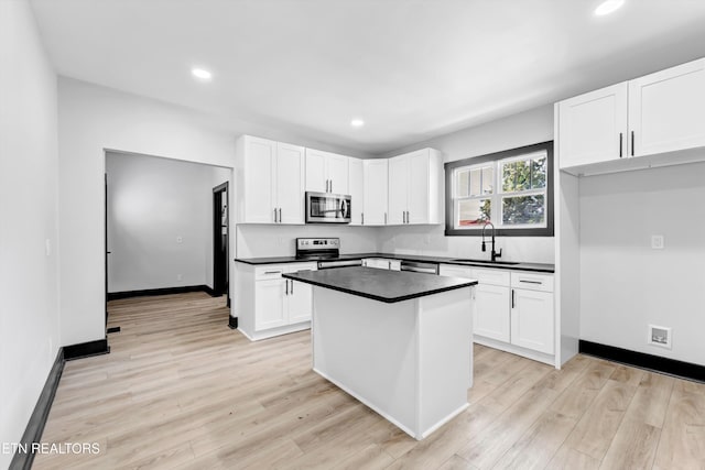 kitchen featuring stainless steel appliances, a kitchen island, sink, light hardwood / wood-style floors, and white cabinetry