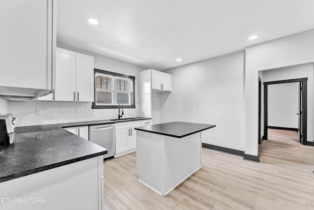 kitchen featuring a center island, backsplash, sink, stainless steel dishwasher, and white cabinetry