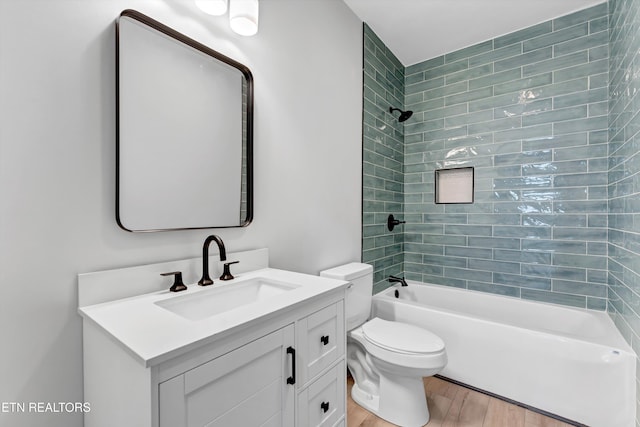 full bathroom featuring toilet, vanity, wood-type flooring, and tiled shower / bath