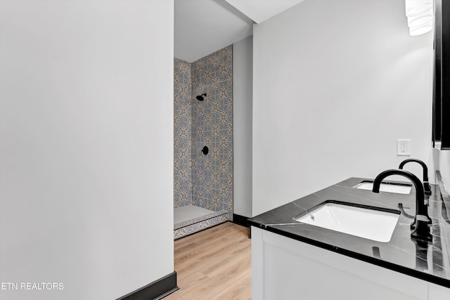 bathroom with vanity, a tile shower, and wood-type flooring