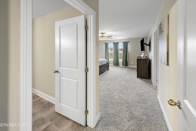 hall featuring light carpet and a textured ceiling