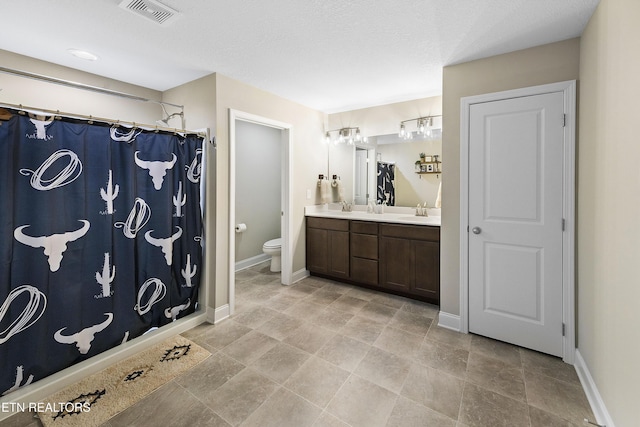 bathroom with a shower with curtain, vanity, toilet, and a textured ceiling