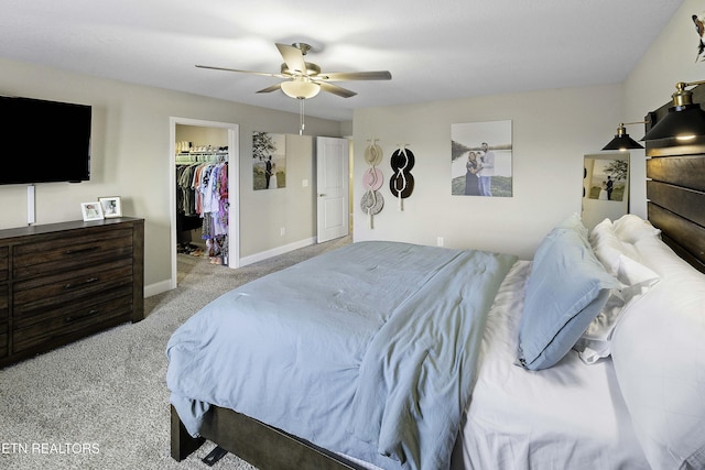 bedroom featuring light carpet, a walk in closet, a closet, and ceiling fan