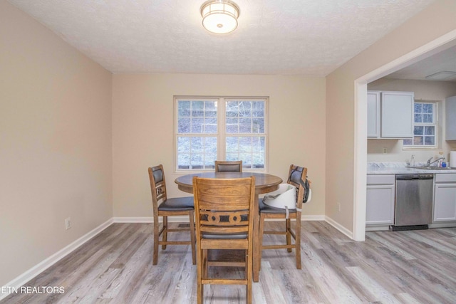 dining space with light hardwood / wood-style flooring and a textured ceiling