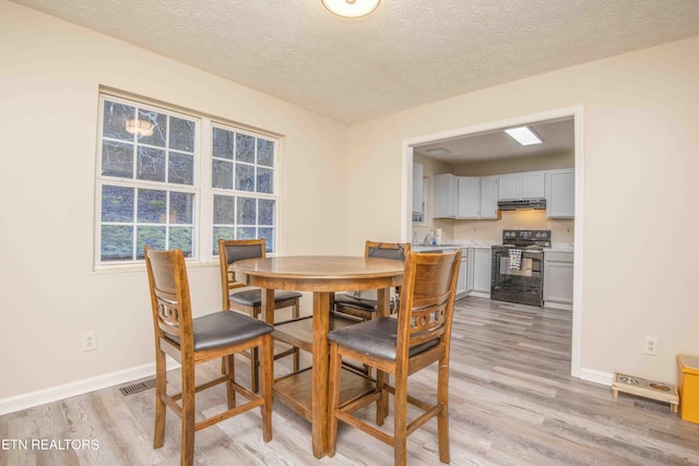 dining area with sink, light hardwood / wood-style flooring, and a textured ceiling