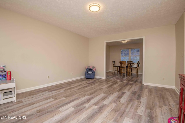 spare room with a textured ceiling and light hardwood / wood-style floors