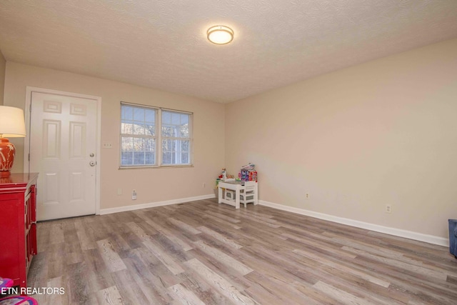 empty room with a textured ceiling and light hardwood / wood-style floors