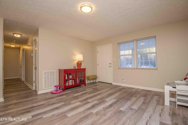 foyer entrance with hardwood / wood-style floors and a textured ceiling