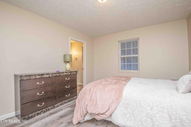 bedroom with light hardwood / wood-style floors and a textured ceiling