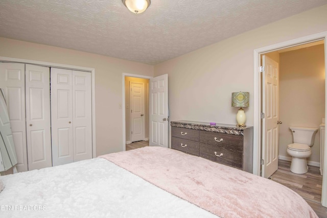 bedroom with ensuite bathroom, a textured ceiling, a closet, and light hardwood / wood-style flooring