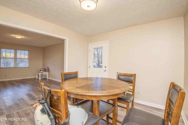 dining space with plenty of natural light, a textured ceiling, and dark hardwood / wood-style flooring