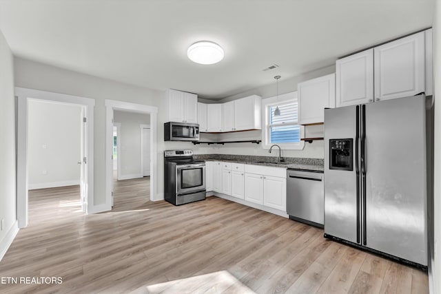 kitchen featuring stainless steel appliances, sink, pendant lighting, light hardwood / wood-style flooring, and white cabinetry