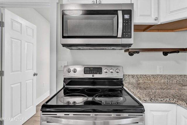 kitchen featuring light stone counters, white cabinetry, light wood-type flooring, and appliances with stainless steel finishes