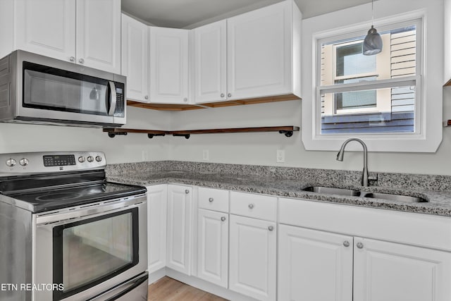 kitchen featuring appliances with stainless steel finishes, stone countertops, white cabinetry, and sink