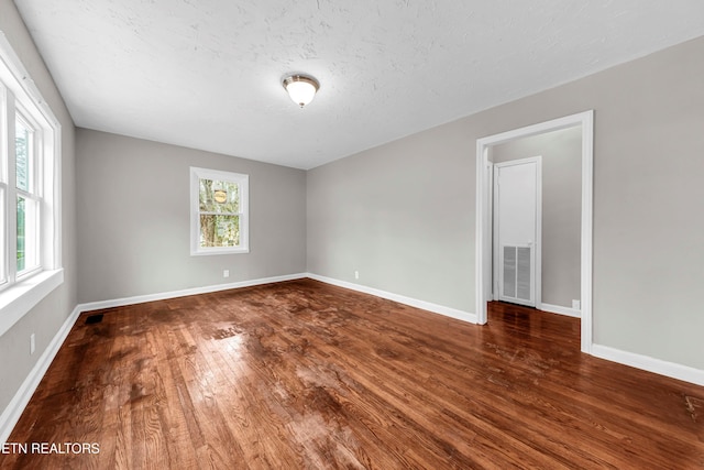 spare room with a textured ceiling and dark hardwood / wood-style floors