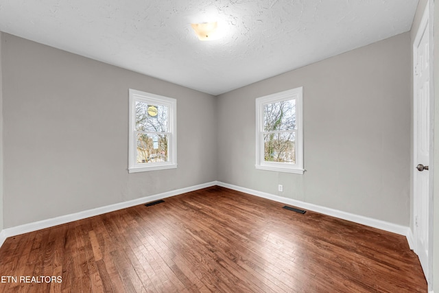 unfurnished room with hardwood / wood-style floors and a textured ceiling