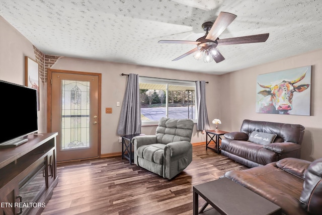 living room featuring ceiling fan, dark hardwood / wood-style flooring, and a textured ceiling