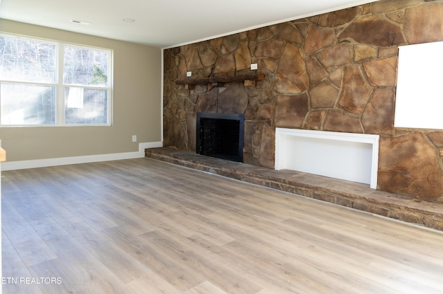 unfurnished living room featuring a stone fireplace and light wood-type flooring