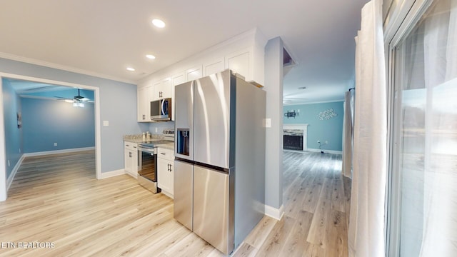 kitchen with light wood-style flooring, a high end fireplace, white cabinetry, ornamental molding, and appliances with stainless steel finishes