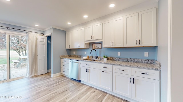 kitchen with stainless steel dishwasher, white cabinets, a sink, light stone countertops, and light wood-type flooring