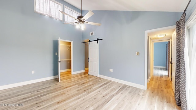 unfurnished bedroom featuring light wood-style floors, visible vents, baseboards, and a barn door