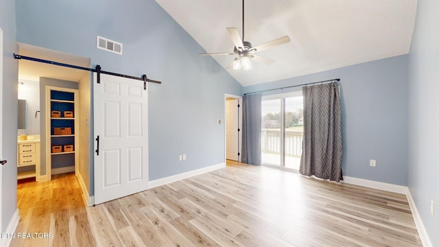 unfurnished bedroom with visible vents, a barn door, light wood-style floors, access to outside, and baseboards