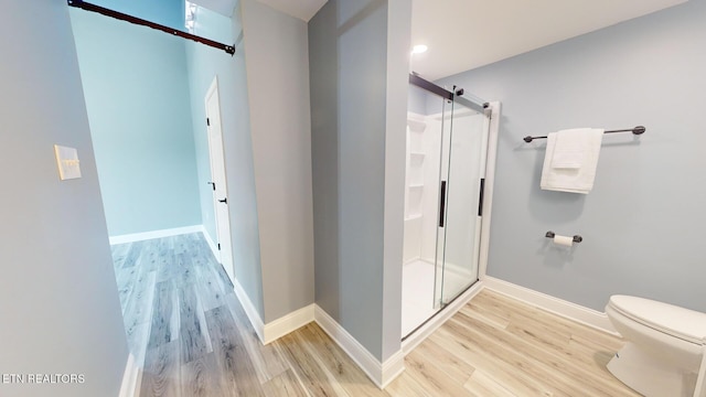 bathroom featuring a shower stall, wood finished floors, and baseboards