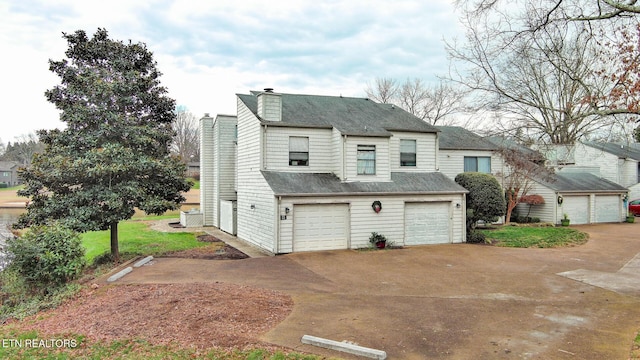 exterior space featuring a garage, a shingled roof, and a chimney