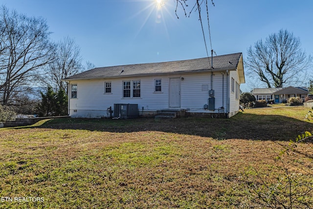 rear view of house featuring central air condition unit and a lawn