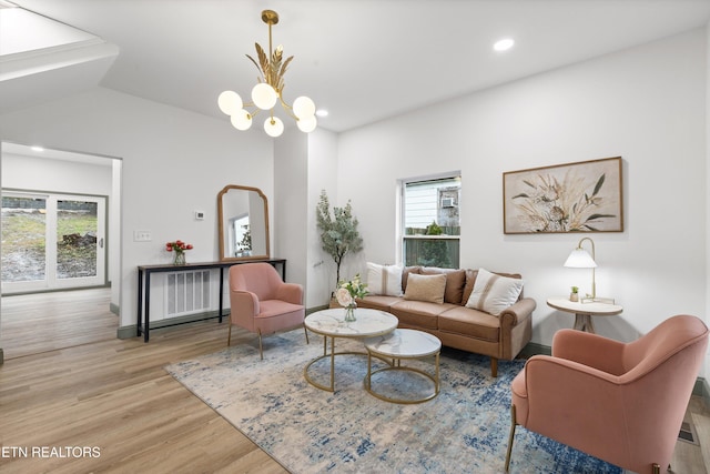 living room featuring light hardwood / wood-style floors, vaulted ceiling, and an inviting chandelier