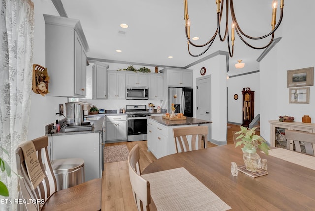 kitchen featuring appliances with stainless steel finishes, pendant lighting, a kitchen island, and crown molding