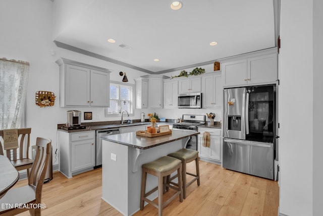 kitchen featuring a breakfast bar, stainless steel appliances, a kitchen island, and light hardwood / wood-style floors