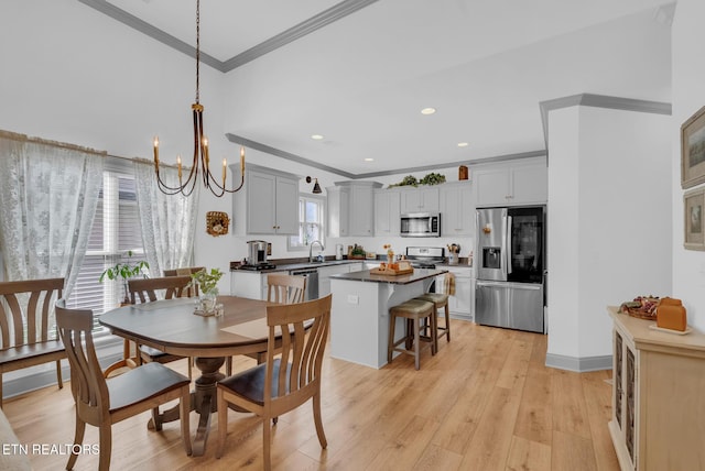 dining room featuring light hardwood / wood-style floors, an inviting chandelier, ornamental molding, and sink