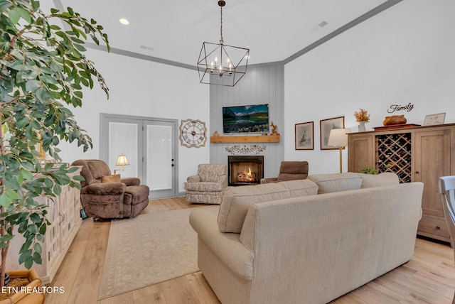 living room with ornamental molding, light wood-type flooring, a fireplace, and a chandelier